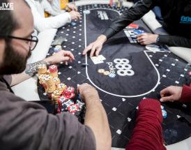 Players competing at an 888poker live table, with chip stacks and cards visible